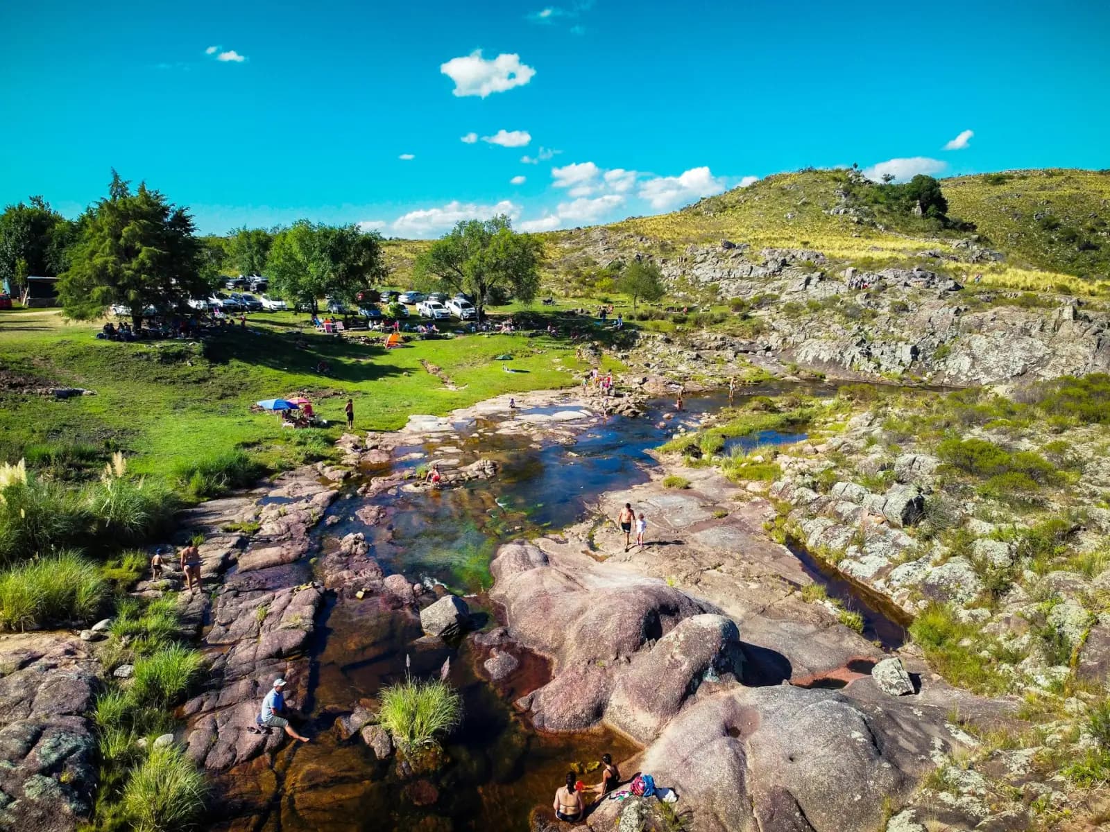 A clear rocky river winding through the green Sierras de Córdoba on a summer day