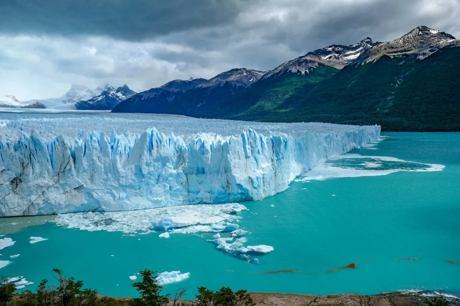 The blue ice face of the Perito Moreno Glacier calving into turquoise Lago Argentino in Patagonia
