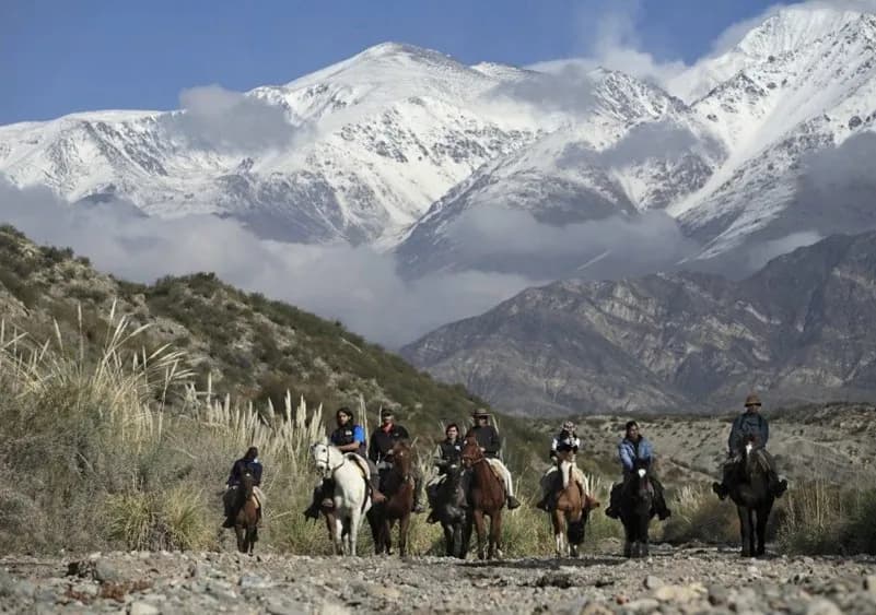 Group of tourists horseback riding through the foothills of the Andes in Mendoza