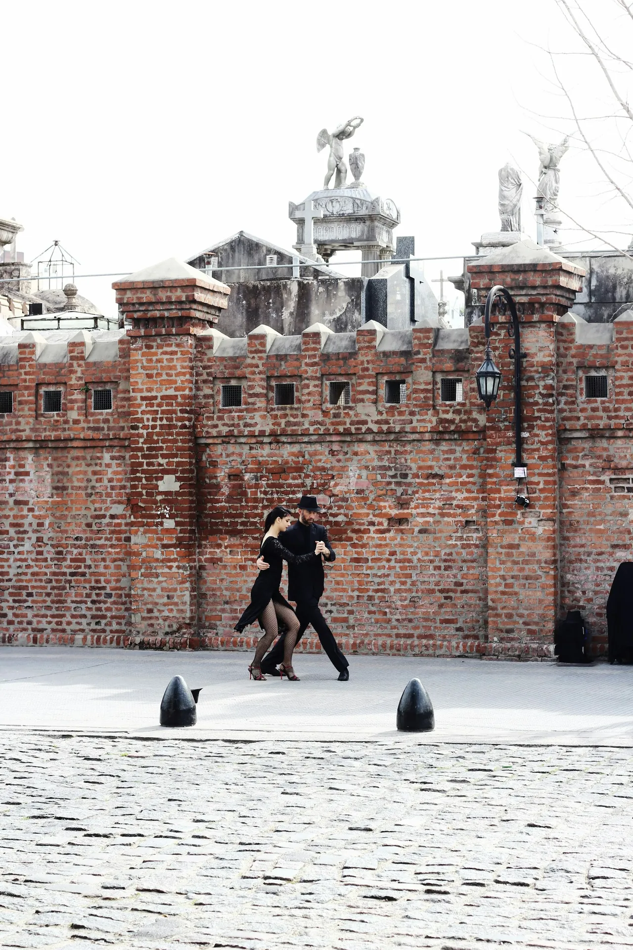 Professional tango couple dancing on the cobblestone streets near Recoleta Cemetery, showcasing the authentic cultural experiences in Buenos Aires.