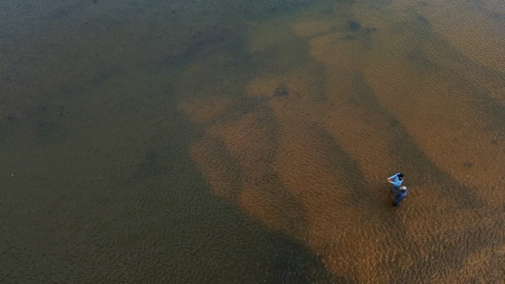 Drone shot of two anglers wading and fly fishing in the shallow waters of Corrientes wetlands