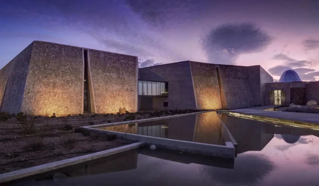 Modern stone architecture of Bodega Zuccardi Valle de Uco reflected in water at twilight