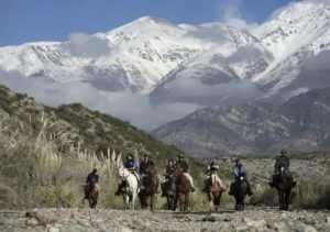 Group of tourists horseback riding through the rugged foothills of the snow-capped Andes mountains in Mendoza