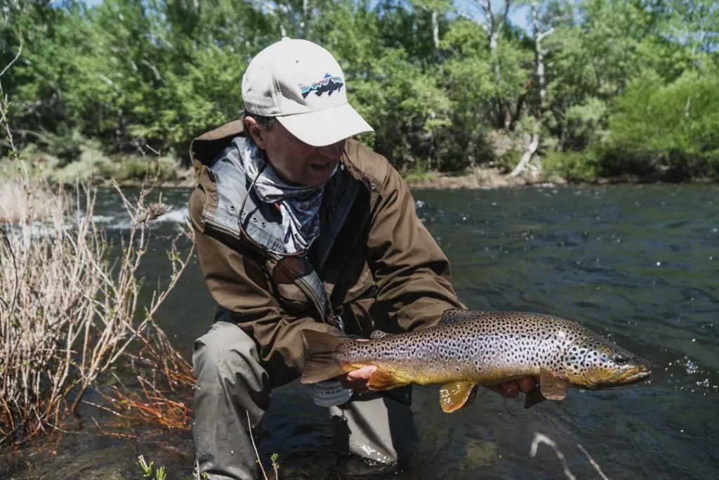 Angler smiling while holding a beautiful Brown Trout catch in the river
