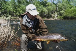Angler smiling while holding a beautiful Brown Trout catch in the river