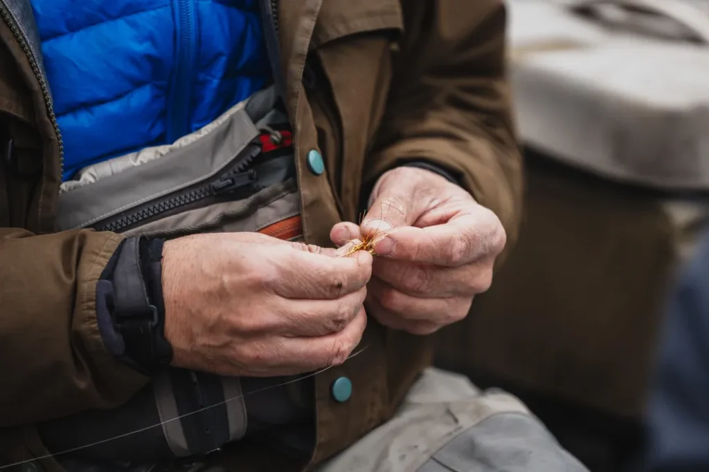 Close-up of fishing guide's hands expertly tying a fly fishing knot on the leader