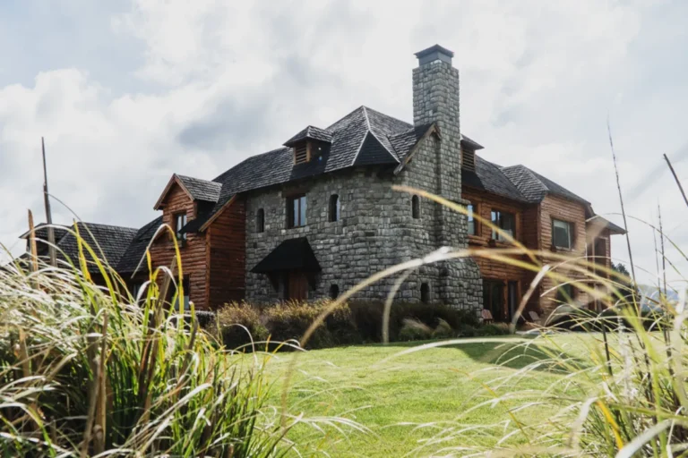 Exterior view of a grand stone and timber fishing lodge nestled in the Patagonia landscape